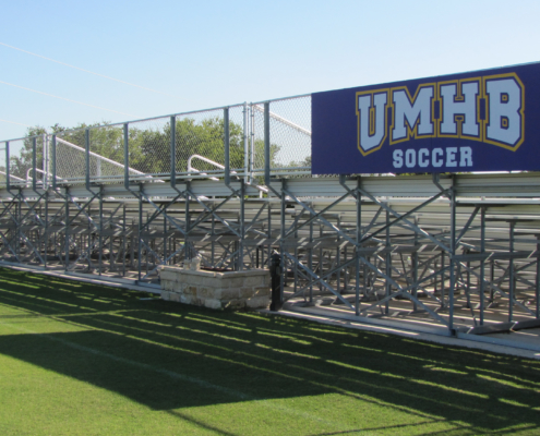 UMHB Wayfinding Large sign attached to fencing behind stadium bleachers