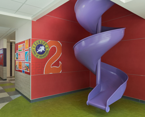 Pomeroy Elementary School Wall panels near spiral purple slide featuring bright vivid cultural graphics